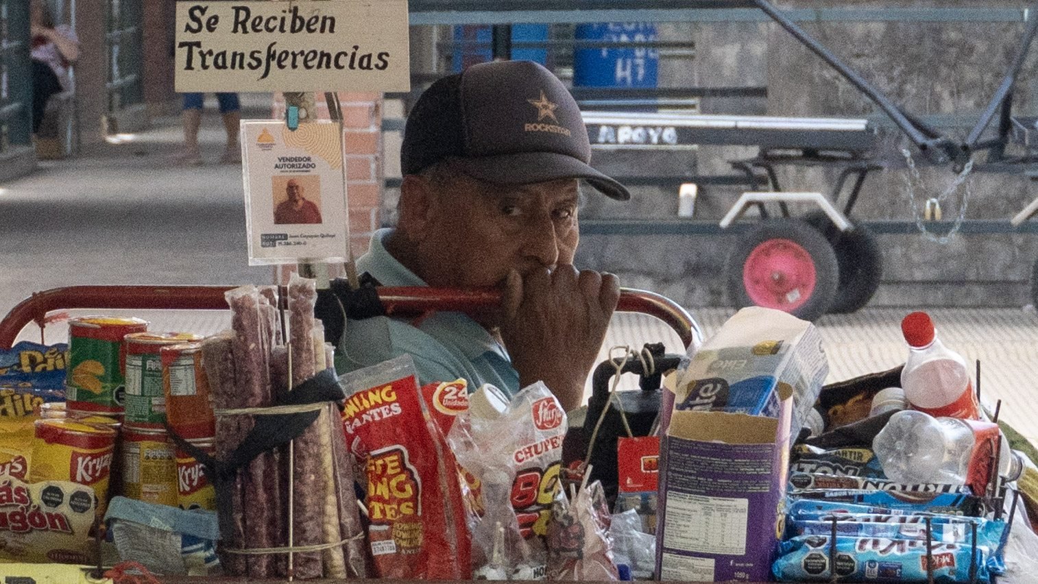 Vendedor junto a un carrito de golosinas y embutidos en la calle.